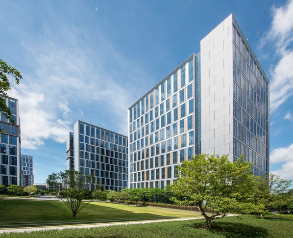 A modern building with a glass facade, surrounded by a well-maintained lawn and trees.