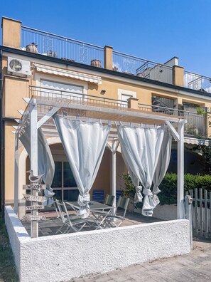 Un espace extérieur abrité, aménagé avec des tables et des chaises, et agrémenté d’une enseigne accueillante.