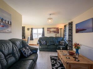 Ein Wohnzimmer mit zwei Ledersofas, einem Holztisch und einer Kronleuchter.