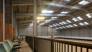 An indoor riding arena with a wooden floor, metal railings, and a high ceiling with skylights. - 3 Bed in Dereham (oc-65903) (Foulsham)