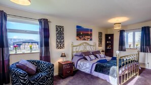 A bedroom with a bed, a chair, a nightstand, a lamp, a window with curtains, and artwork on the walls. - 3 Bed in Dereham (oc-65903) (Foulsham)