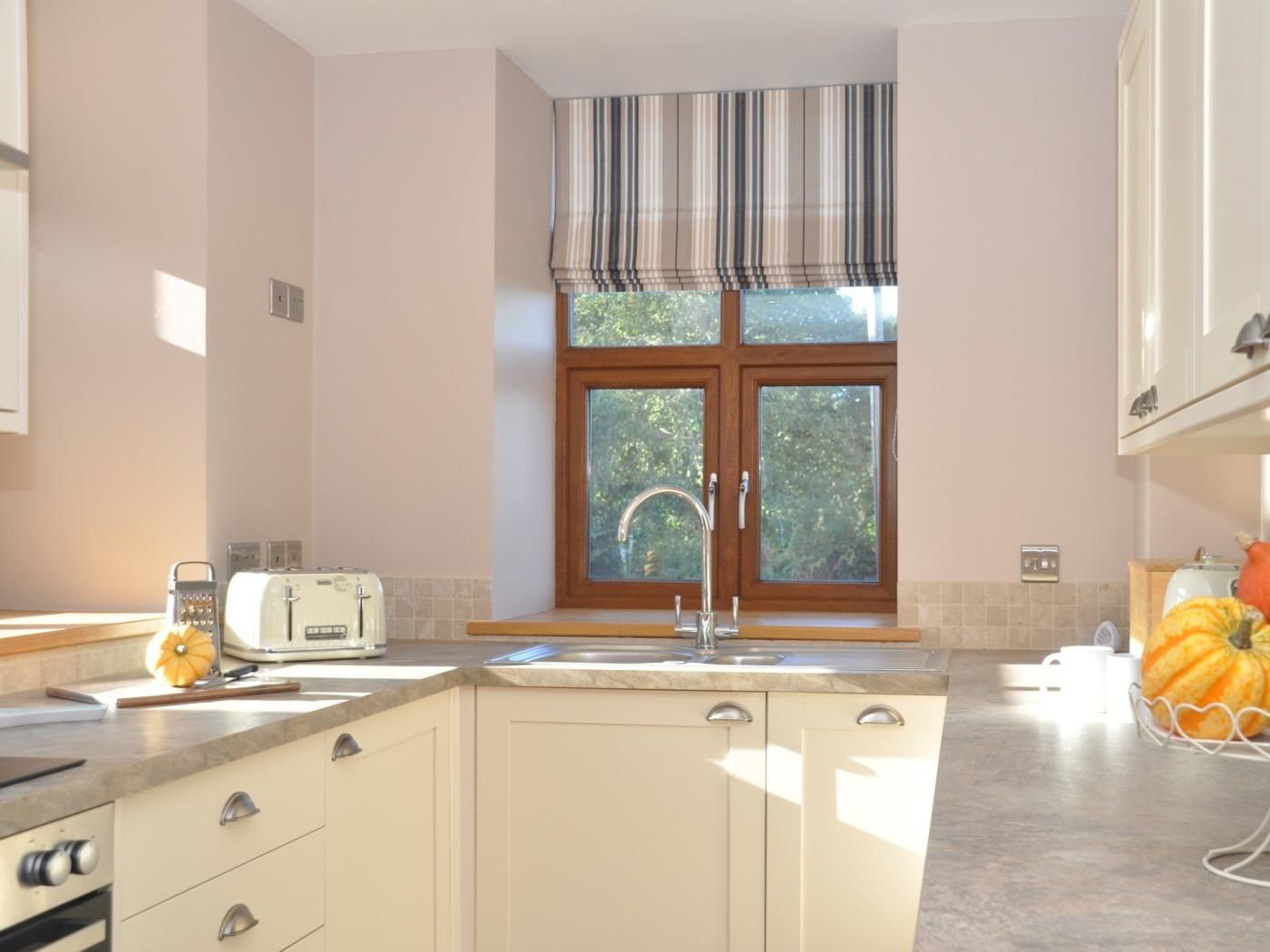 A kitchen with a window, a sink, a toaster, and a cabinet.