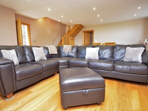 Ein modulares Sofa mit passendem Hocker, Holzboden und einer Treppe.