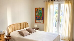 Ein Bett mit weiß-blauer Bettdecke, zwei Kissen, einem Holz-Kopfteil, einem Nachttisch mit Lampe und einem Poster an der Wand.