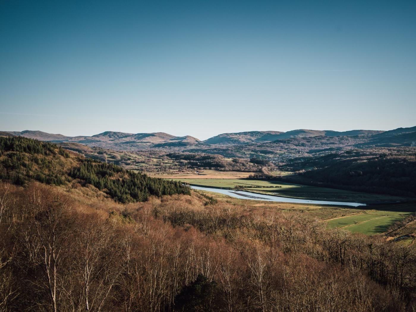 Eine Landschaft mit Fluss, Hügeln und spärlicher Vegetation.