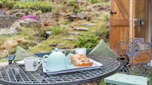Une table ronde en métal, avec une théière, une tasse et une miche de pain.