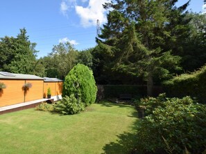 A residential area with a wooden house, a well-maintained lawn, and dense trees. - 1 Bed in Knaresborough (oc-66981) (Knaresborough)