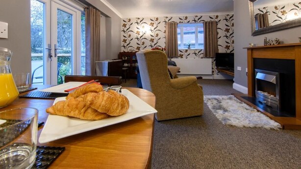 Una sala de estar con una mesa de comedor, un sofá, una chimenea y un ventanal con cortinas.
