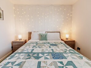 A bedroom with a bed, two bedside tables, a nightstand, a wall-mounted light fixture, and a framed picture. - 3 Bed in Rye- (oc-72303) (Camber)