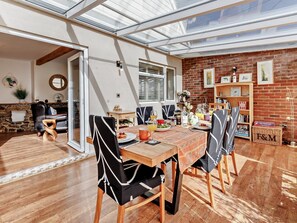 A dining area with a wooden table, black and white patterned chairs, and a brick wall with bookshelves. - 3 Bed in Rye- (oc-72303) (Camber)