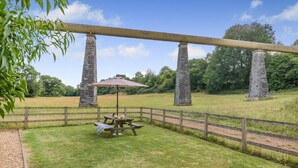 A picnic table with a canopy, surrounded by a wooden fence, under stone pillars, with a grassy field and trees in the background. - 2 Bed in Bristol (oc-72582) (Winford)