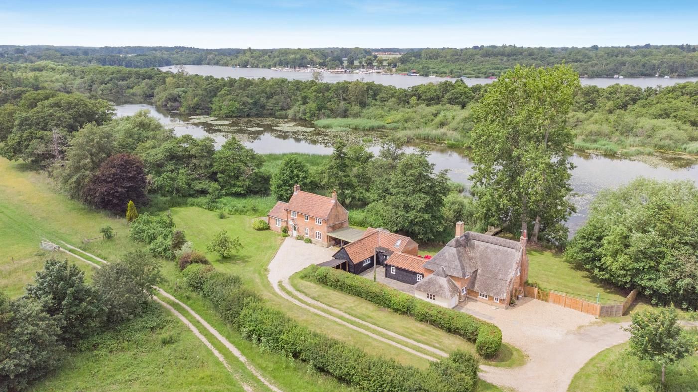 A large house with a garden and a view of a lake.