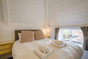 A neatly made bed with pillows, a bedside table, and a window with curtains. - 6 Bed in Norwich (oc-72652) (Hoveton)