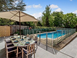 An outdoor pool area with a table and chairs, a covered umbrella, and a fenced pool. - 5 Bed in Woodbridge (oc-72724) (Woodbridge)