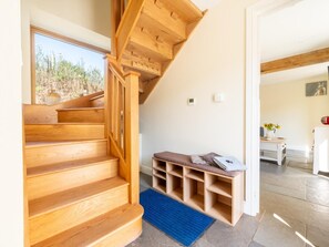 Eine Holztreppe führt zu einem Raum mit einer Sitzbank und Blick ins Freie.