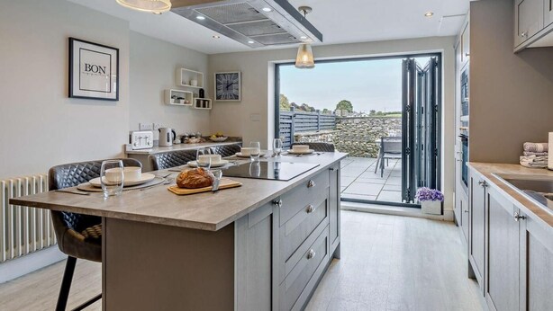 Una cocina moderna con una isla central, iluminación colgante y vistas al exterior.