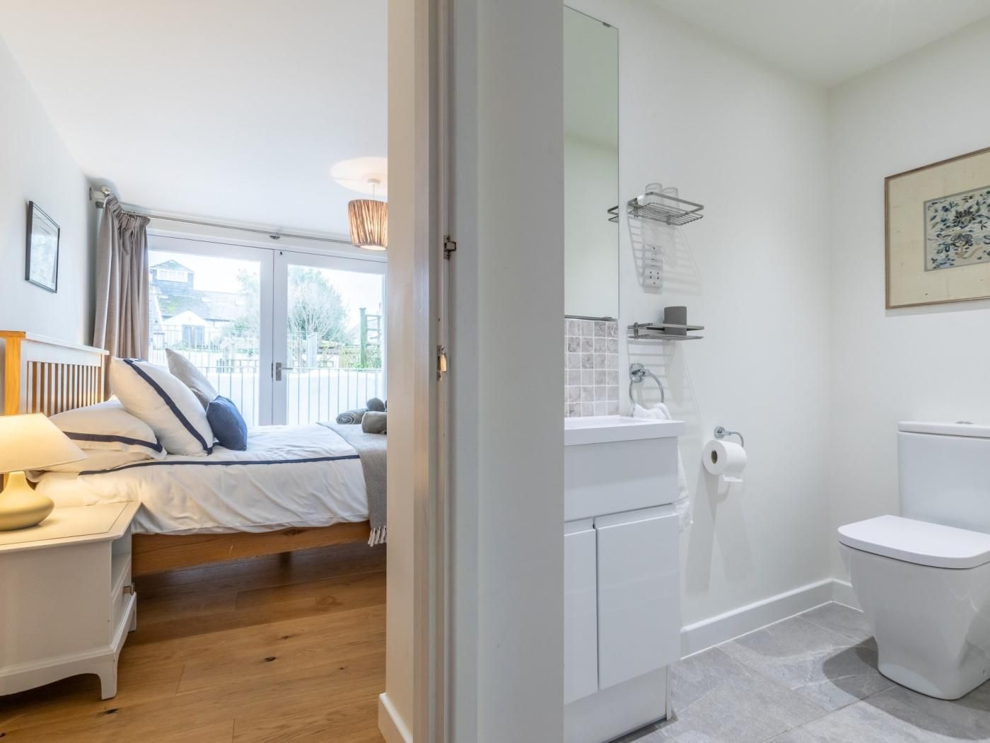 A bedroom with a bed, bedside table, and a view of the outside.