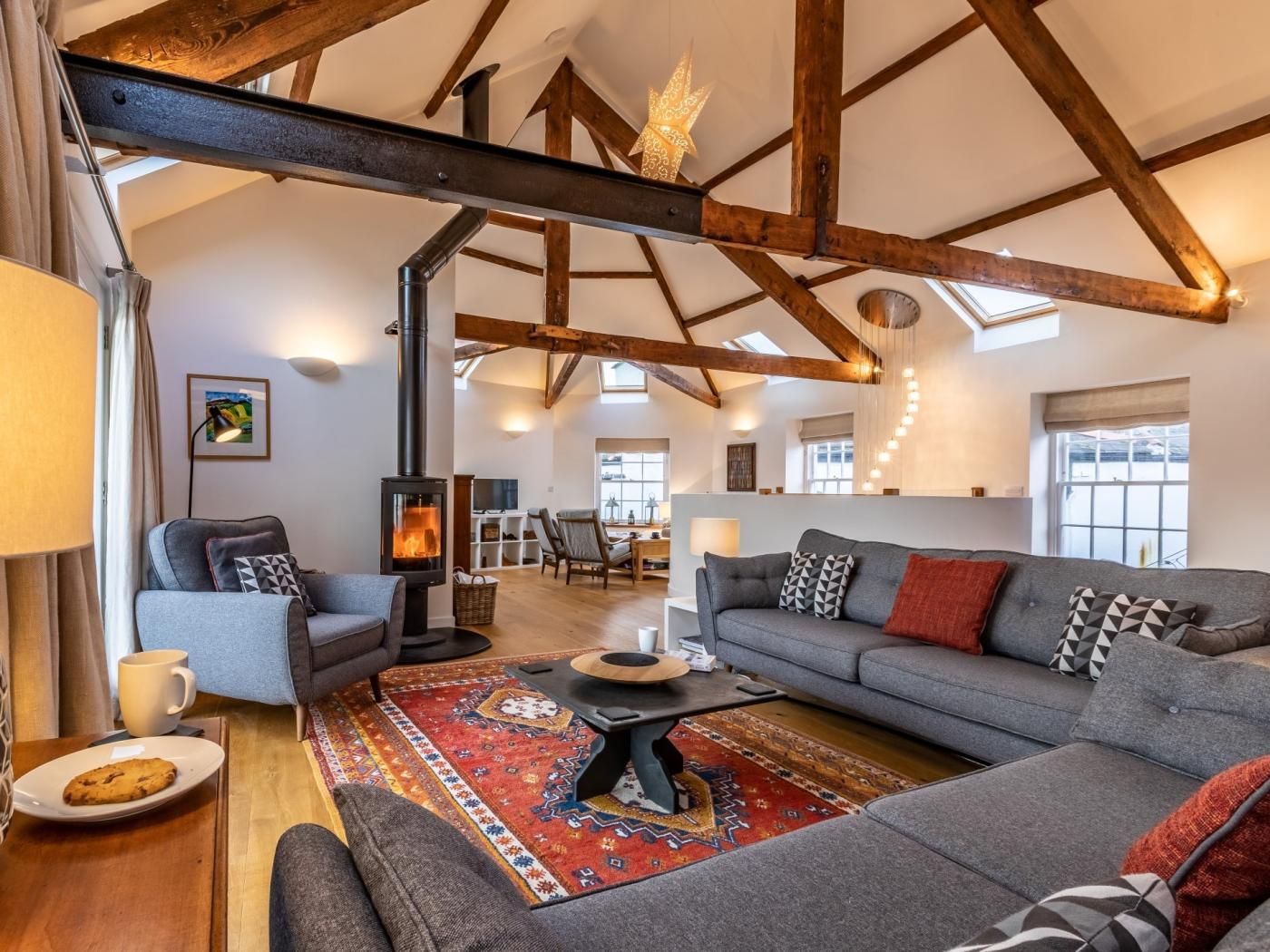 A spacious living room with a large fireplace, a sofa set, and a patterned rug.