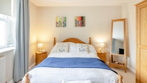 Ein Schlafzimmer mit einem Bett, zwei Nachttischen, einem Spiegel und Bildern an der Wand.