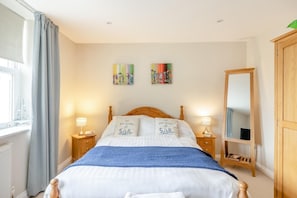 Ein Schlafzimmer mit einem Bett, zwei Nachttischen, einem Spiegel und Bildern an der Wand.