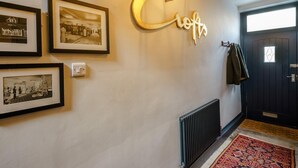 A hallway with framed black and white photographs, a wall-mounted sign, a radiator, and a patterned rug. - 4 Bed in Harrogate (oc-73424) (Harrogate)
