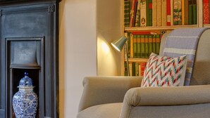 A room with a fireplace, a bookshelf, a lamp, and a patterned throw pillow. - 4 Bed in Harrogate (oc-73424) (Harrogate)
