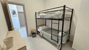 A bunk bed with a small table and a trash bin in a room with white walls and a door leading to another room. - Estia Chios Apartment B3 (Lefkonia)