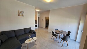 A living room with a sofa, a coffee table, and a dining area with chairs and a table. - Estia Chios Apartment B3 (Lefkonia)