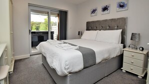 Una camera da letto moderna con un letto grande, un comodino, una scrivania e un balcone.