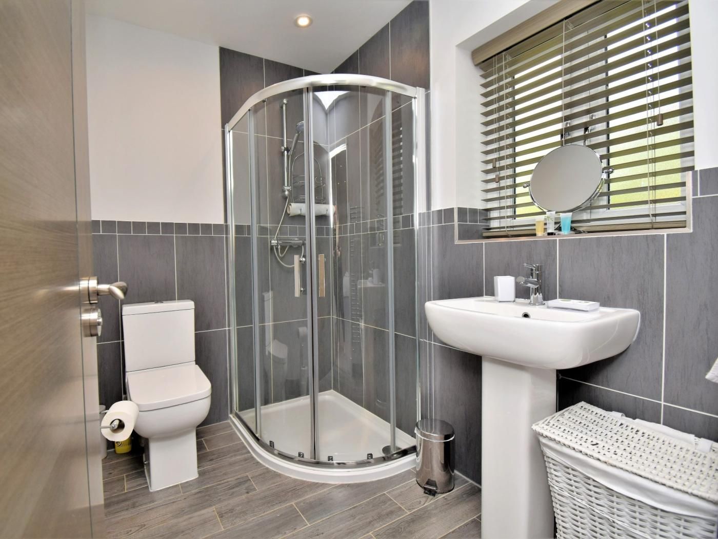Un bagno moderno con cabina doccia in vetro, lavandino bianco e toilette.