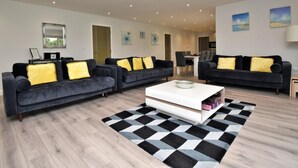 Ein stilvolles Wohnzimmer mit zwei dunklen Sofas, einem weißen Couchtisch und einem schwarz-weißen Teppich.
