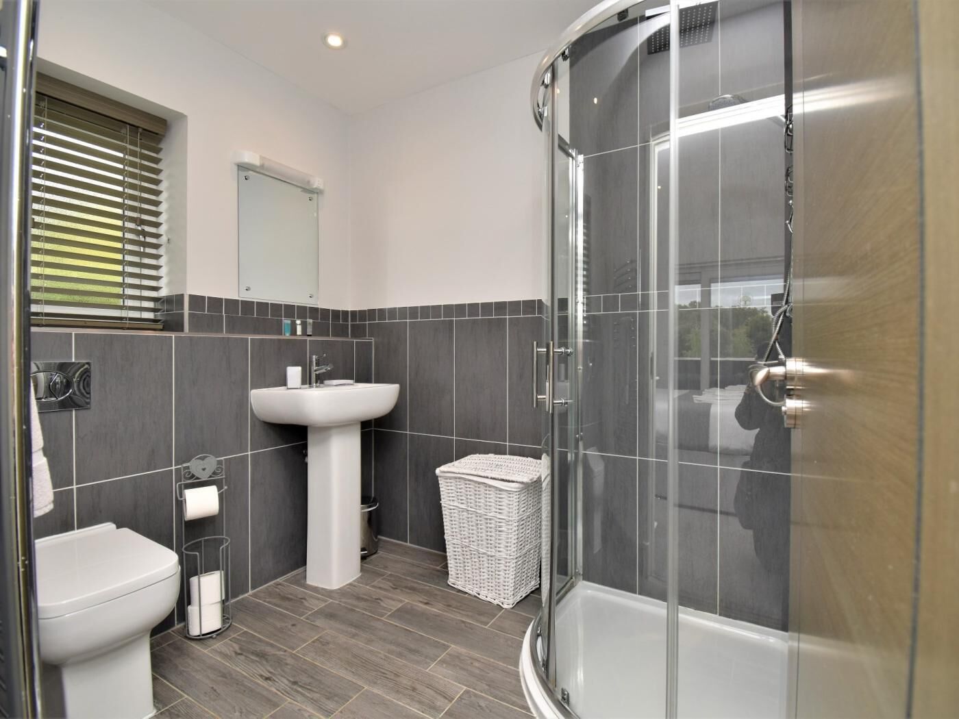 A modern bathroom with a glass shower enclosure, a white sink, and a toilet.