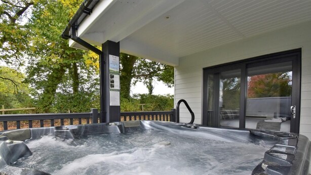 Ein Whirlpool mit Wasserfall, eine überdachte Terrasse und eine Glastür, die zu einem Außenbereich führt.