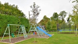 Ein Spielplatz mit Schaukeln, einer Rutsche und einem kleinen Gebäude.