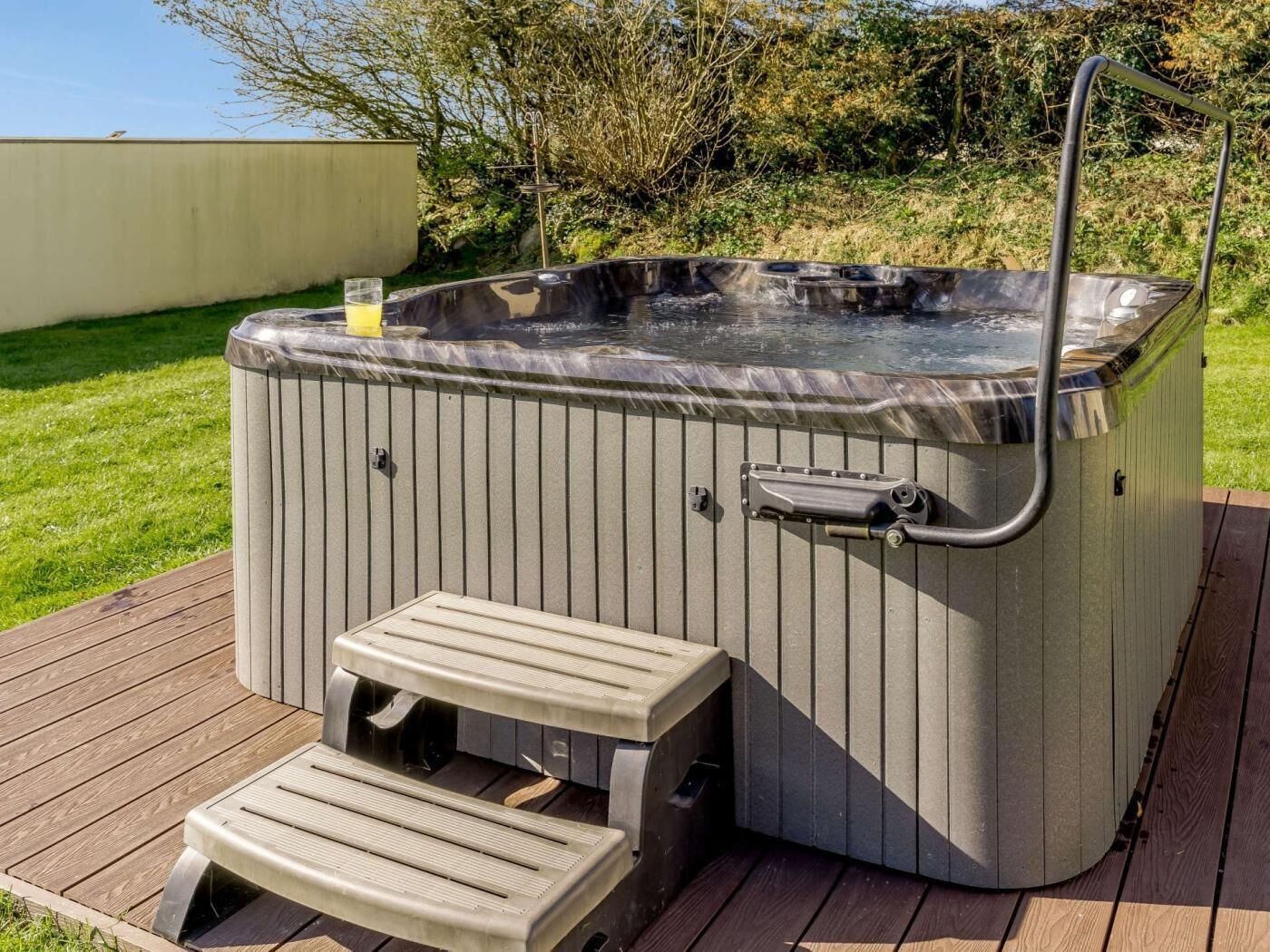Un bain à remous doté d’un banc intégré, entouré d’une terrasse en bois.
