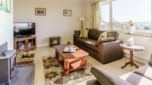 Ein Wohnzimmer mit Fernseher, Sofa, Couchtisch und Kamin.