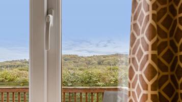 Un balcon donnant sur un paysage boisé, avec une balustrade en bois et une chaise.