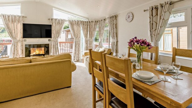A room with a sofa, dining table, chairs, a flat-screen TV, and a fireplace.