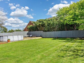 Ein Garten mit Rasen, einer Betonmauer und einem Gebäude mit rotem Dach.