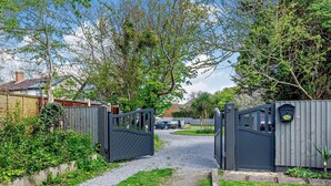 Un camí residencial que condueix a un portal tancat amb un sender de grava.