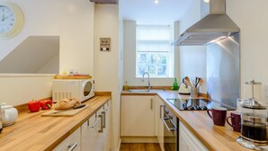 Uma cozinha moderna com bancadas de madeira, micro-ondas, pia e exaustor de aço inoxidável.