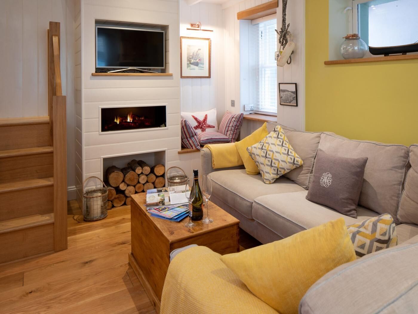 A cozy living room with a fireplace, a television, and a sofa with patterned cushions.