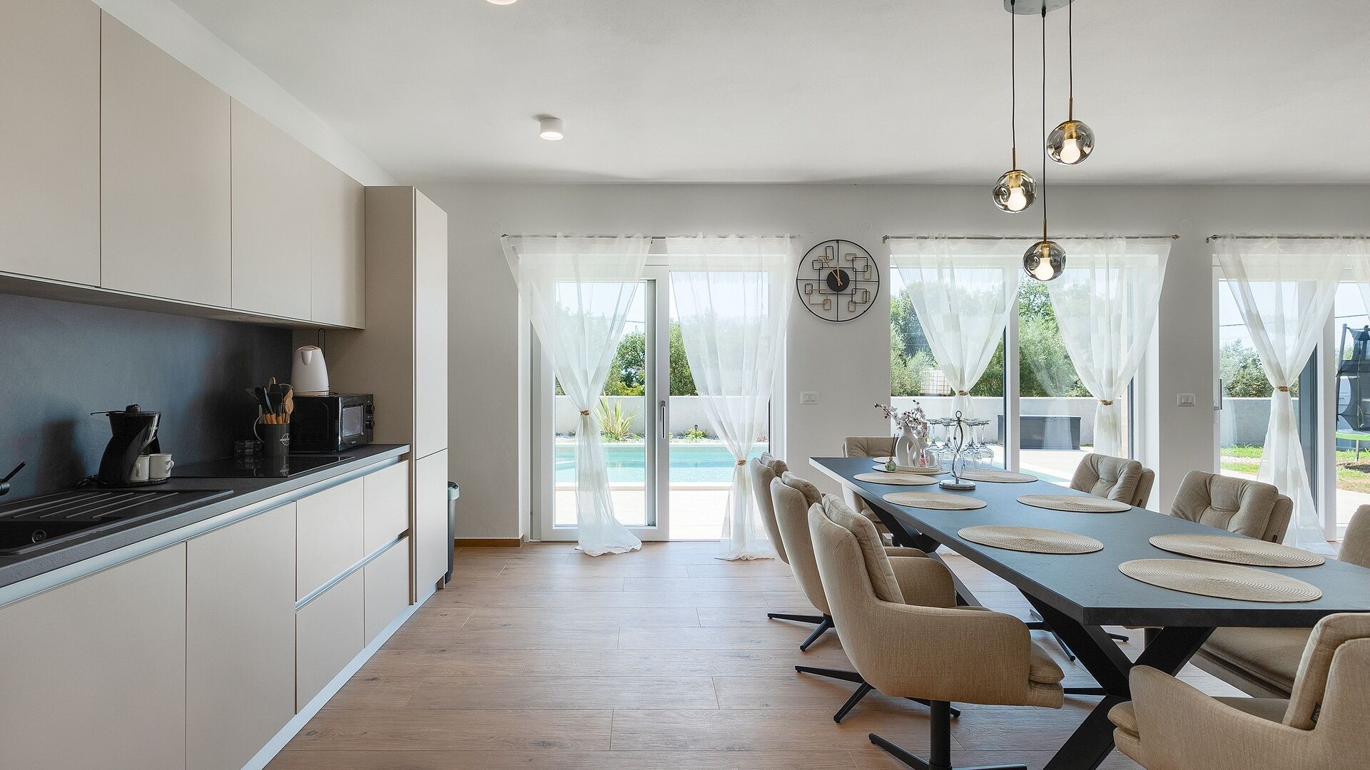 Une cuisine moderne avec un coin repas, de grandes fenêtres et une vue sur une piscine.