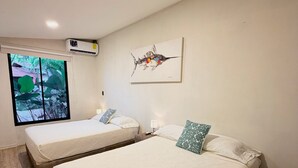 A room with two beds, a window with a view, an air conditioning unit, and a ceiling light. - Tropical Apartments (Puerto Viejo de Talamanca)