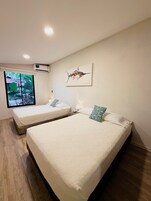 Una habitación con dos camas, ventana con vistas, aire acondicionado y una lámpara en el techo.