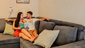 A modern living room with a grey sofa, a green pillow, and a poster on the wall. - Tropical Apartments (Puerto Viejo de Talamanca)