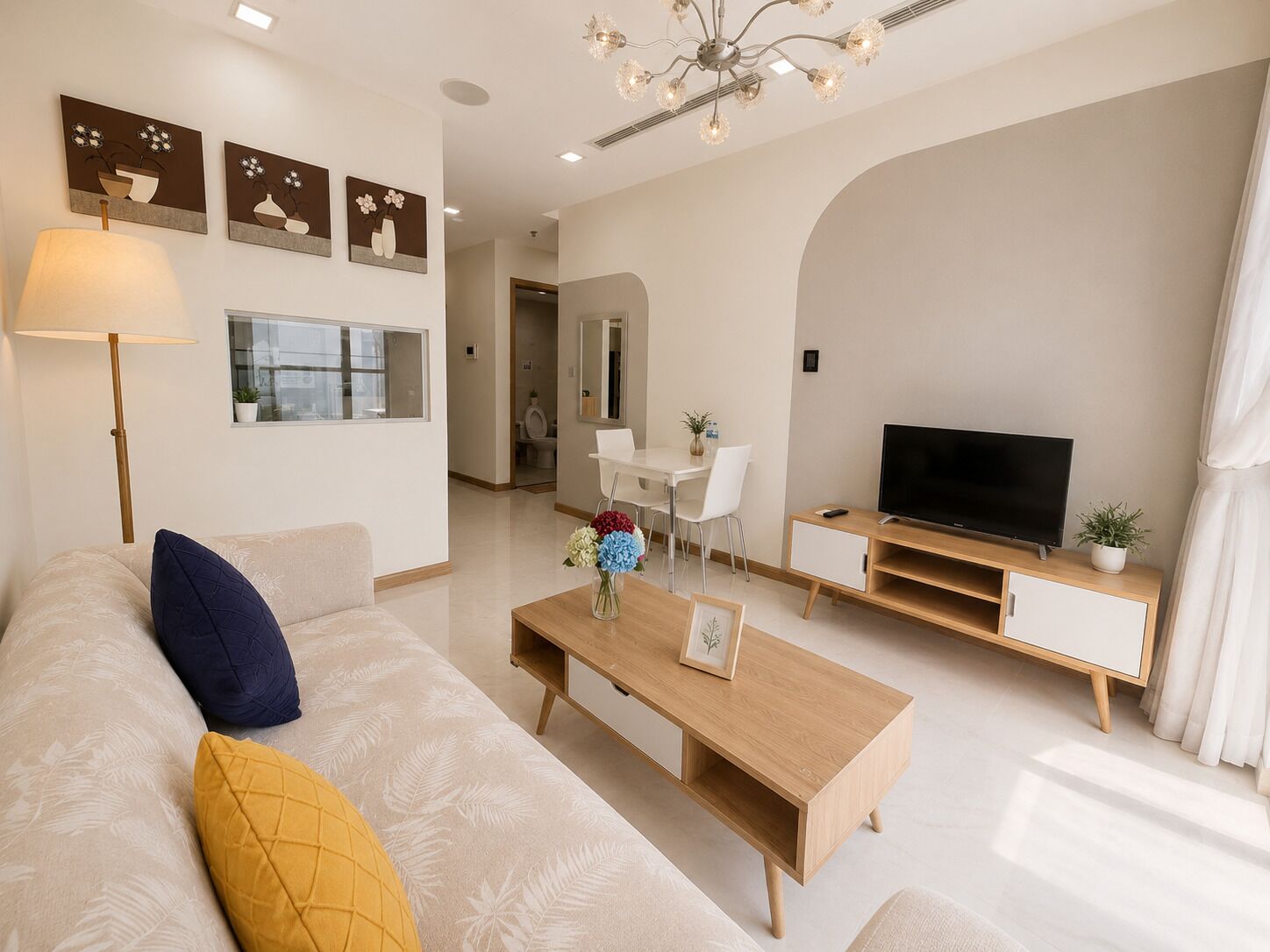 A modern living room with a sofa, coffee table, TV, and dining area.