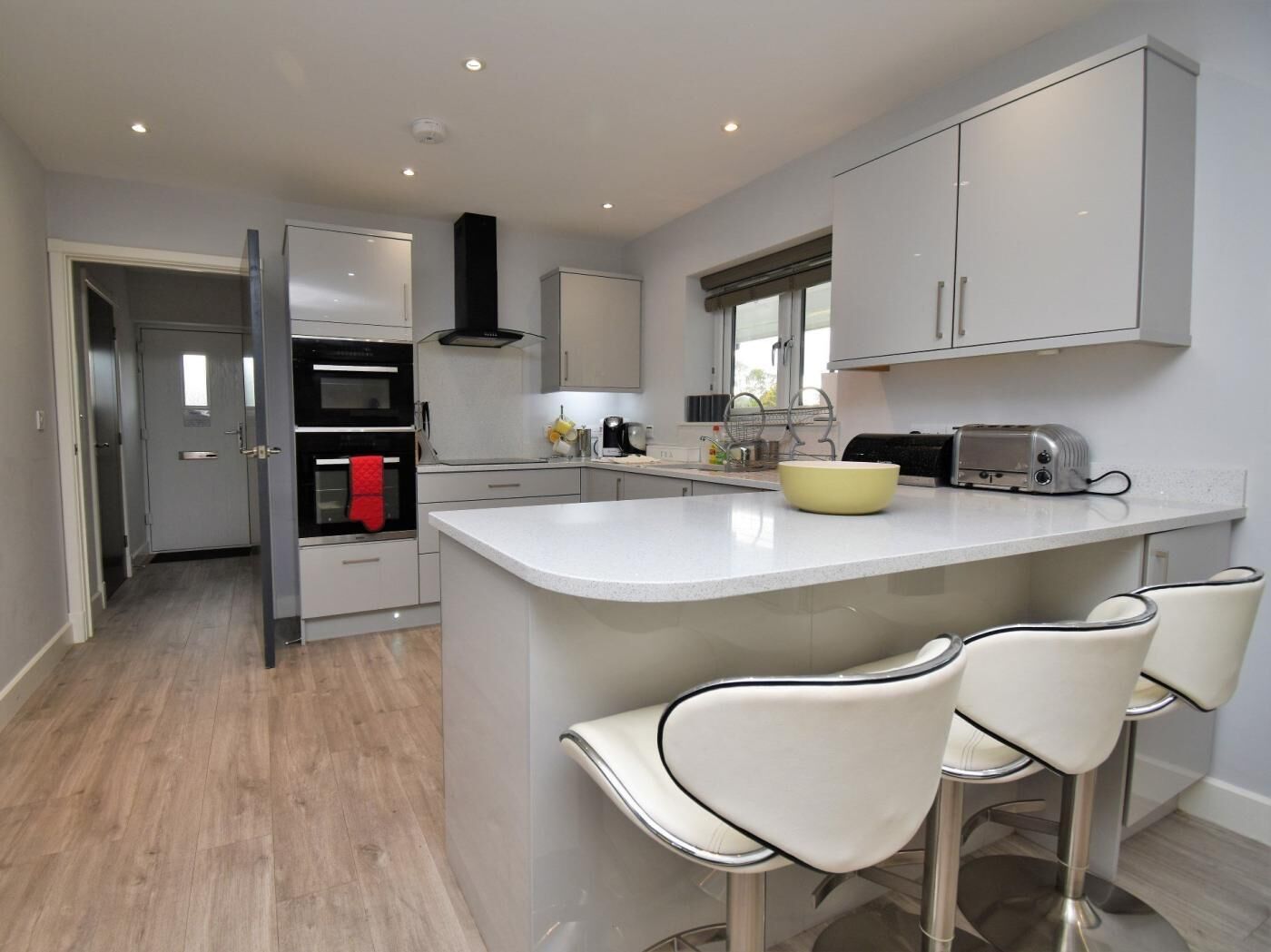 A modern kitchen with a central island, bar stools, a toaster, and a stove.