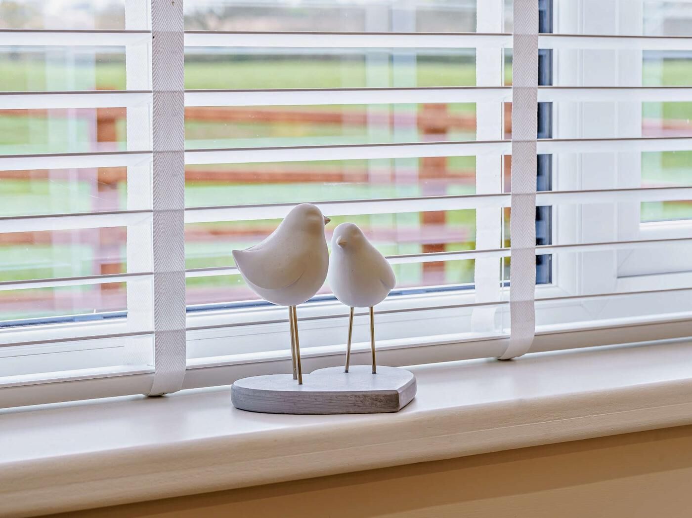 Zwei vogelähnliche Ornamente auf einem Fensterbrett.