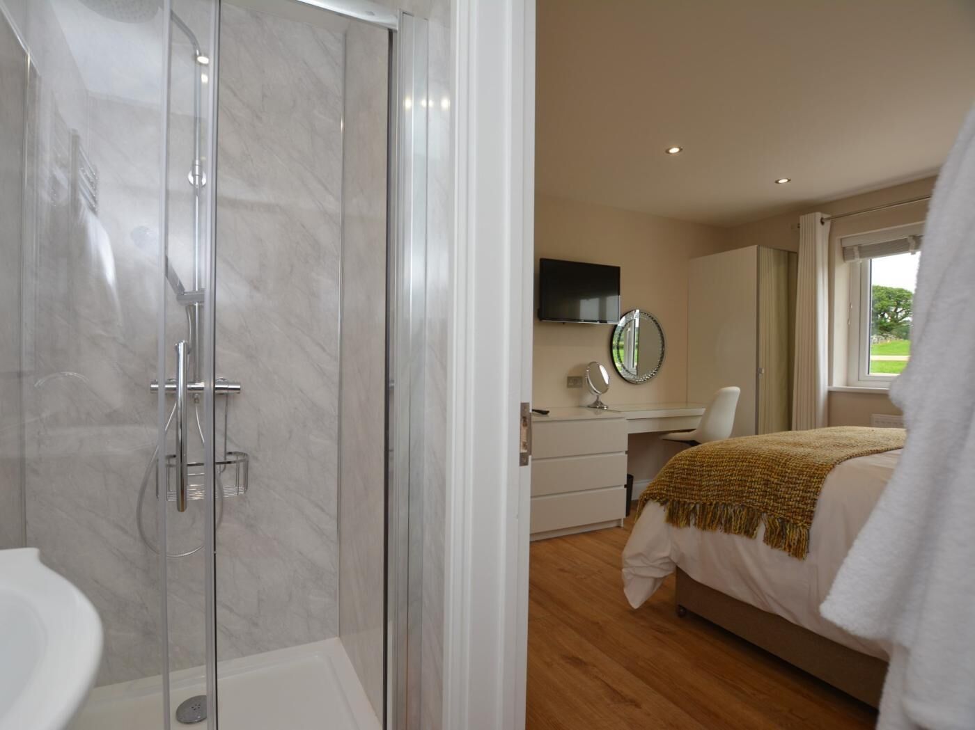 A modern bathroom with a glass-enclosed shower, a white toilet, and a sink.